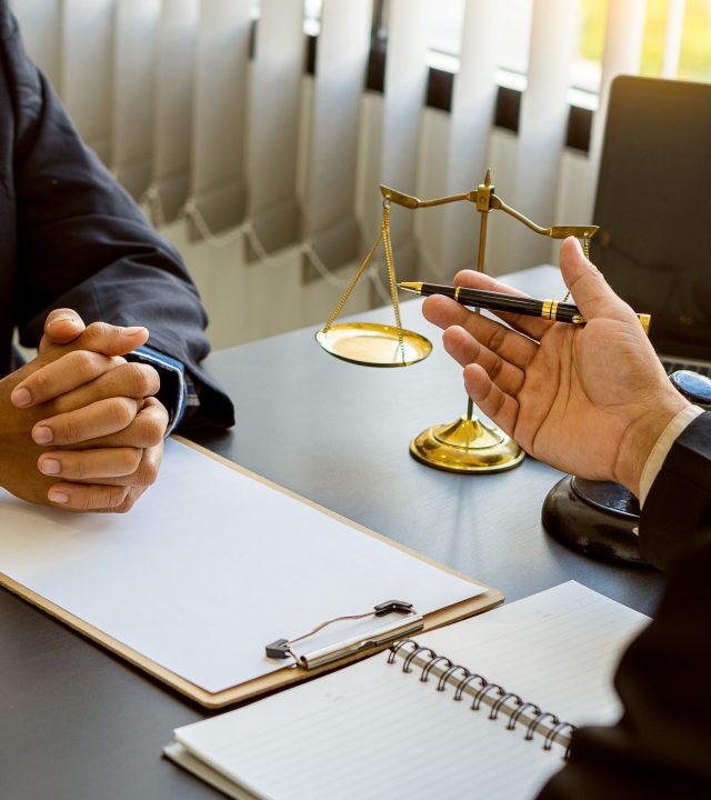 businessmen and lawyers discussing contract businessman and lawyer discussing contract documents sitting at a table legal concept consultants with hammers and scales placed next to each other with a v